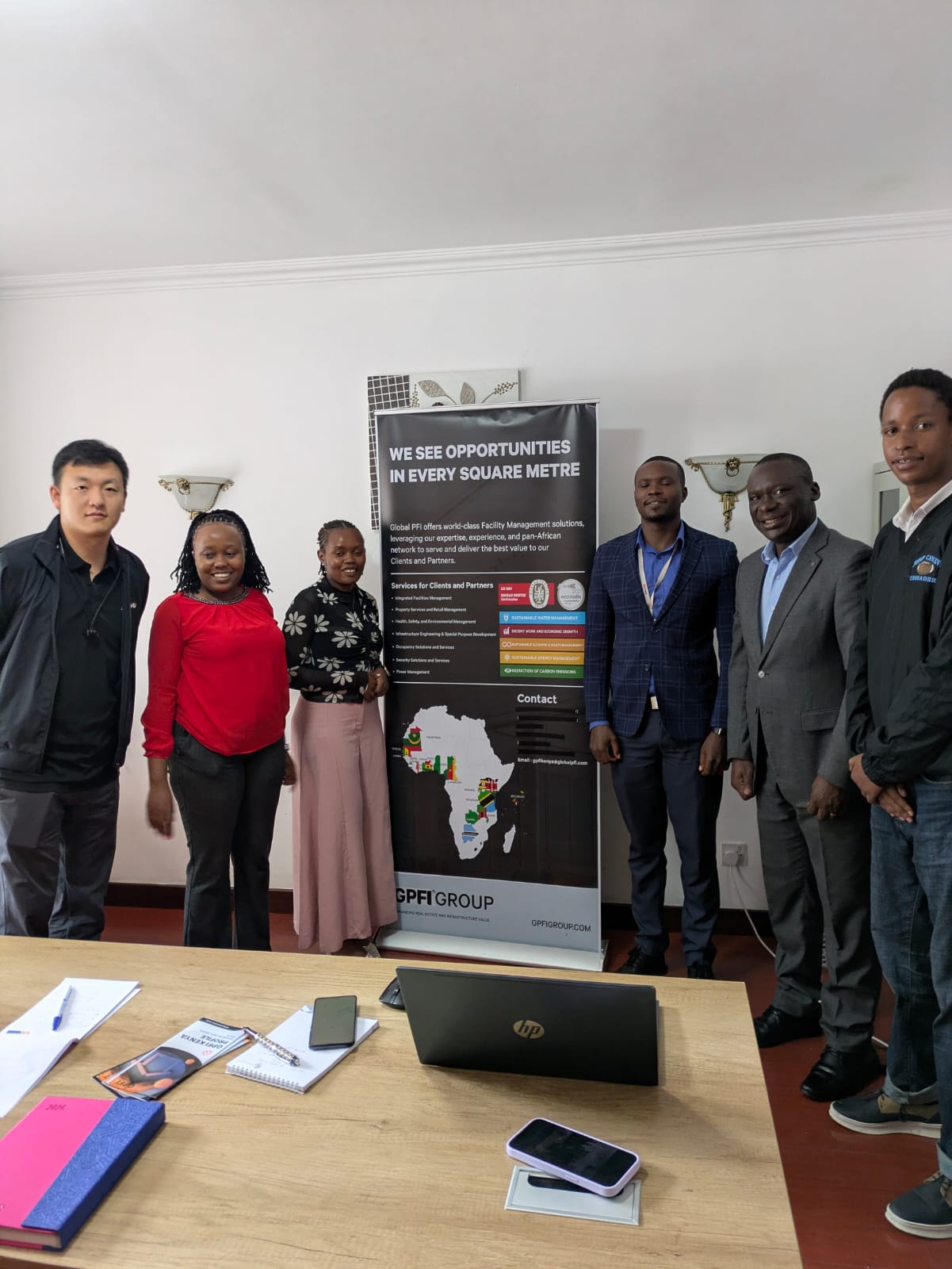 The Global PFI Kenya team beside the company banner